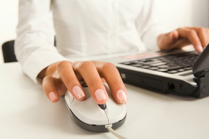 młoda kobieta pracująca na laptopie za pomocą myszki