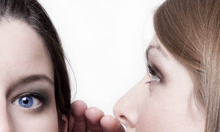 dwie kobiety szepcące sobie do ucha