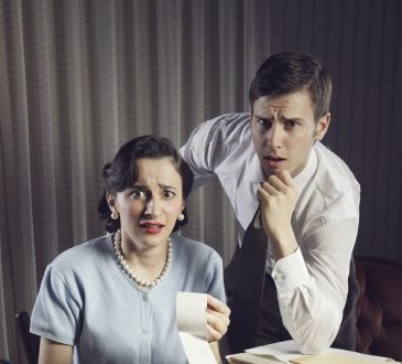 Przerażona kobieta z mężczyzną patrzący na rachunki do opłacenia