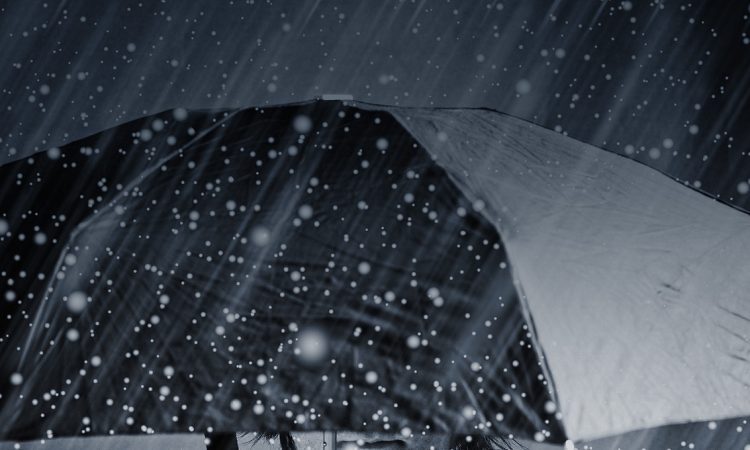 Biznesman stojący w deszczu pod parasolką
