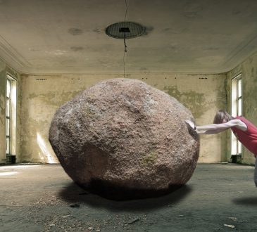 Człowiek próbuje przetoczyć ciężki kamień