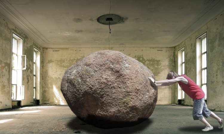 Człowiek próbuje przetoczyć ciężki kamień